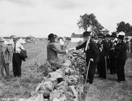 Confederate and Union soldiers shake hands across the wall at the 1938 reunion for the Veterans of the Battle of Gettysburg